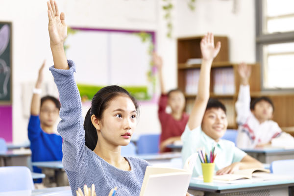 Bambini che alzano la mano in una classe in Cina