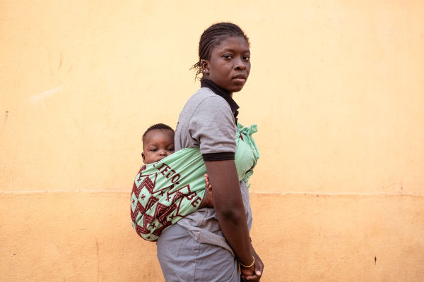 Donna sudanese che porta il figlio sulla schiena